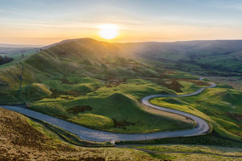 Photo of bird's eye view of a road winding through a green mountain valley