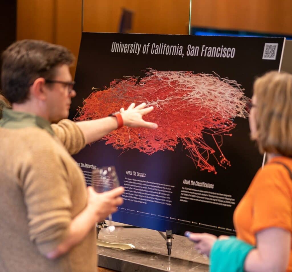 Two attendees admiring the work of Simon Porter -  a poster showing a visual representation of the University of California, San Francisco