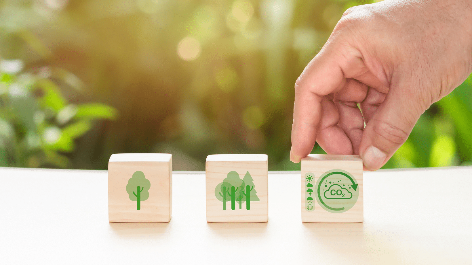 A hand and wood blocks adorned with icons of environmental themes